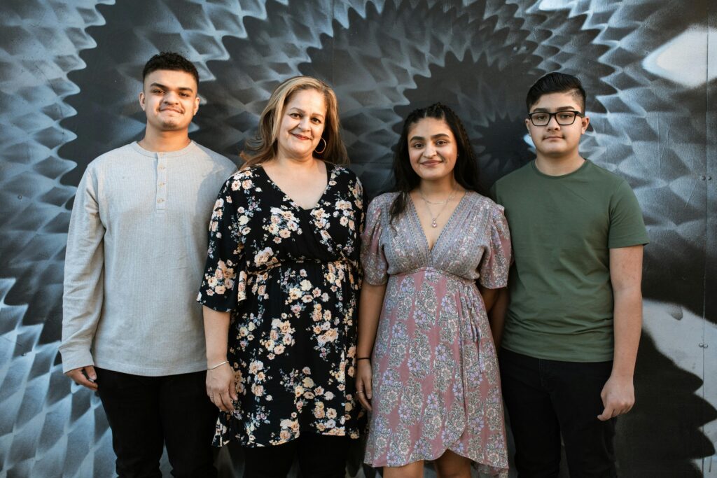 A diverse family of four posing against a stylish graffiti wall. Warm smiles and casual attire highlight the family bond.