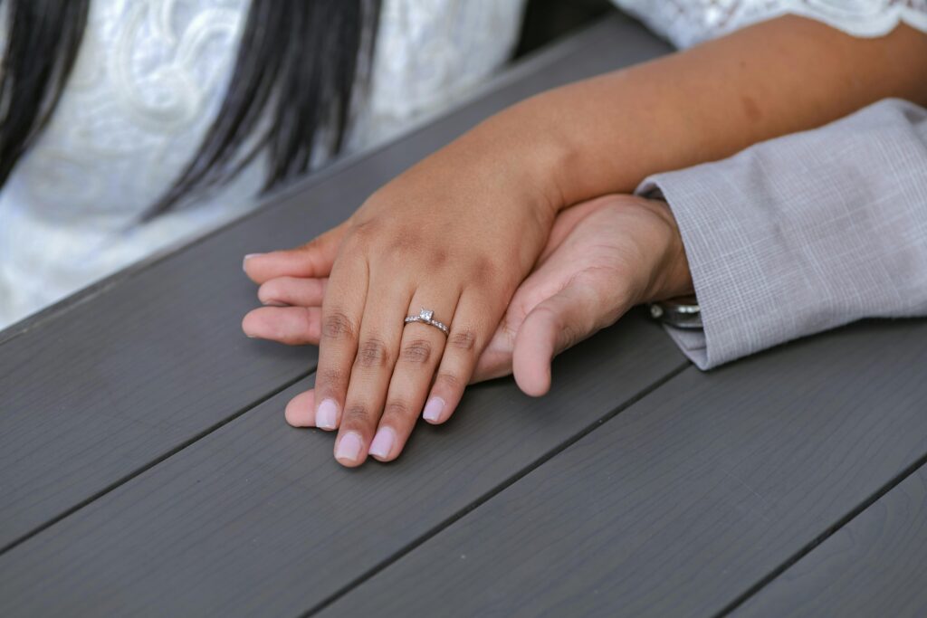 A romantic image showing a couple's hands with an engagement ring on a woman's finger, symbolizing love and commitment.